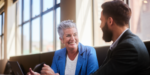 A group of smiling professionals engaged in senior-level mentorship within a workplace setting.