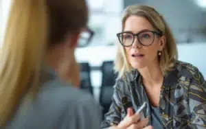 A businesswoman in glasses actively listens during a meeting at the workplace.