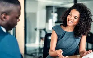 Administrative Professional Career and Workplace Success Skills 2 Smiling businesswoman talking with a colleague at a desk