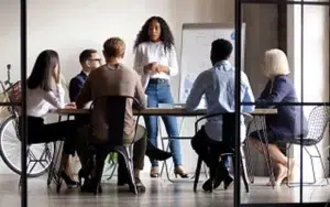 Back-to-Office Transition Essentials for Federal Government Employees 14 Team listening as a leader speaks during an office meeting