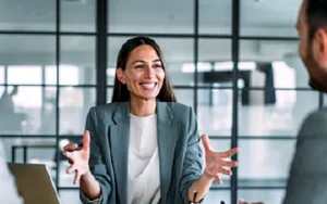 Customer Service Skills: How to Deliver World-Class Experiences 41 Smiling businesswoman gesturing while speaking in a meeting