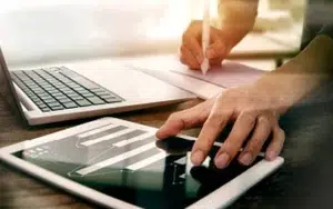 Microsoft Office Excel Intermediate: Leverage Advanced Formulas 18 Hands working on a tablet chart and laptop to analyze spreadsheet data