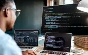 Microsoft Power BI: Data Analysis for Practitioners 19 Developer reviewing code and data dashboards on several screens