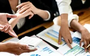 Microsoft Project Basic: Plan and Launch Initiatives Successfully 19 Team planning a project with charts, documents and a calculator on a desk