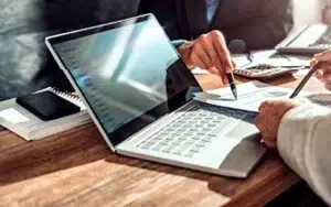 SQL Fundamentals: Introduction to Database Querying 22 Colleagues reviewing a report on a laptop with pens and a calculator
