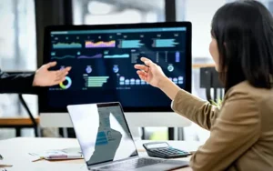 Microsoft Power BI: Data-Driven Analytics for Decision Makers 21 Analyst pointing at a Power BI style dashboard on a monitor while a colleague looks on