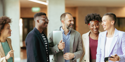 Group of Diverse Coworkers Standing at the Office Corridor and Smiling while Having an Informal Conversation