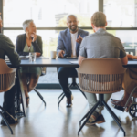 Disability, diversity and business meeting with staff, people or team communication, planning on corporate strategy, goal or mission for KPI. Woman in wheelchair in group talking of company inclusion. - Managing Up