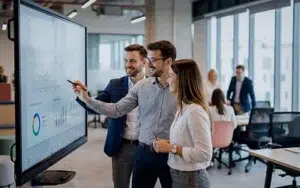 Best Practices for Predictive and Adaptive Project Management 3 Project team reviewing timelines and charts on a large touchscreen in a modern office