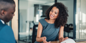 Business women smiling to her male coworker in the office - How To Deliver Effective Performance Reviews - Success Skills for Professional Assistants - Boosting Resilience in the Workplace Series