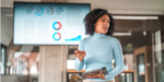 A female executive leader confidently delivering a speech to stakeholders while utilizing modern technology.