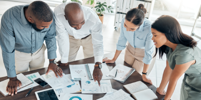 Business people, reviewing data analytics and collaborating in a meeting at the office with graphs, charts or documents.