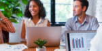 A gathering of corporate professionals convening around a table to analyze data analytics and examine graphical representations.