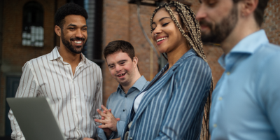 Cheerful young businesspeople with laptop working in office, social inclusion, and adaptive leadership management.