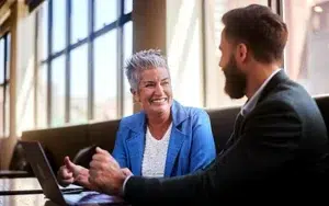 Creating High-Impact Mentor-Mentee Relationships at Work 33 Experienced mentor smiling while talking with a younger colleague at a laptop